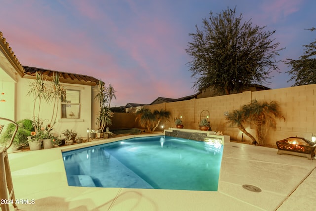 pool at dusk featuring pool water feature