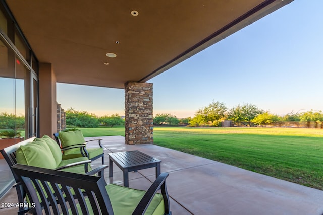 patio terrace at dusk featuring an outdoor living space and a lawn