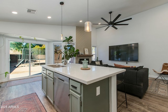 kitchen featuring sink, light hardwood / wood-style flooring, stainless steel dishwasher, pendant lighting, and a kitchen island with sink