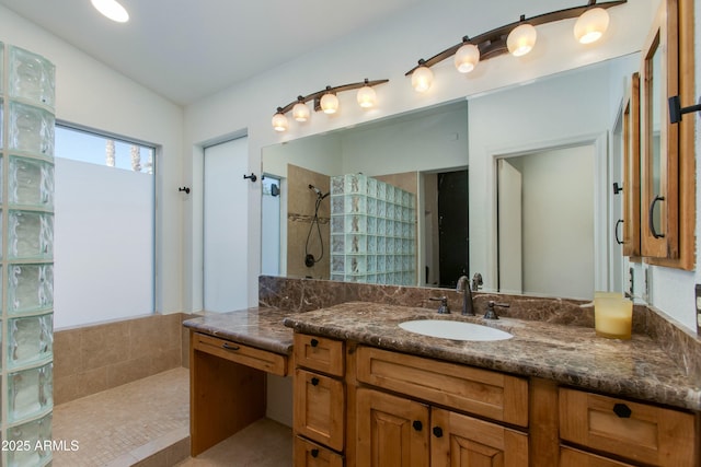 bathroom with tiled shower and vanity