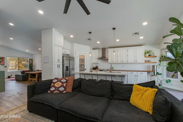 living room with lofted ceiling, sink, light hardwood / wood-style floors, and ceiling fan