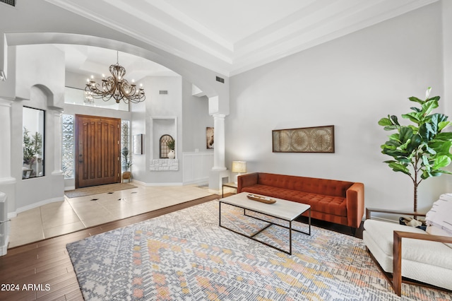 living room with a notable chandelier, wood-type flooring, a high ceiling, and decorative columns