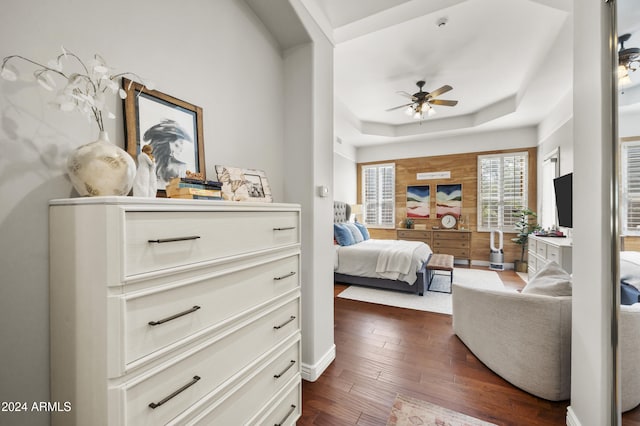 bedroom featuring ceiling fan, dark hardwood / wood-style flooring, and a tray ceiling