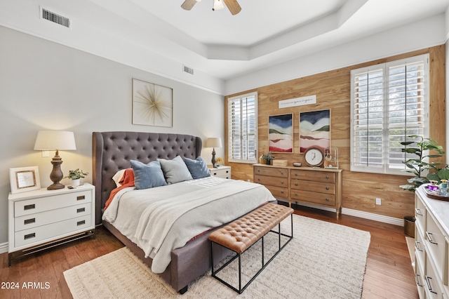 bedroom featuring dark wood-type flooring, wood walls, multiple windows, and ceiling fan