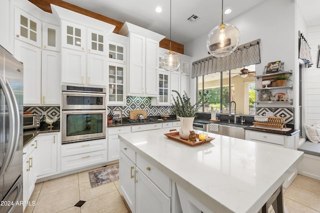 kitchen featuring appliances with stainless steel finishes, tasteful backsplash, light tile patterned floors, white cabinets, and pendant lighting