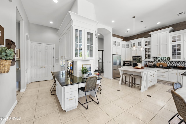 kitchen featuring stainless steel appliances, a breakfast bar area, light tile patterned floors, a center island, and pendant lighting