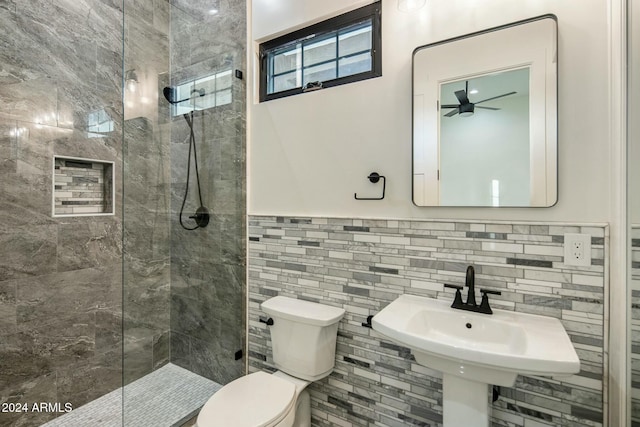 bathroom featuring ceiling fan, sink, tiled shower, tile walls, and toilet