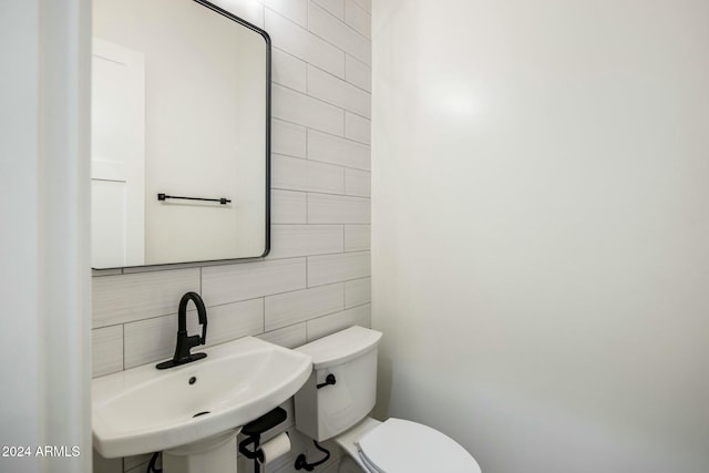 bathroom featuring toilet, sink, tile walls, and backsplash