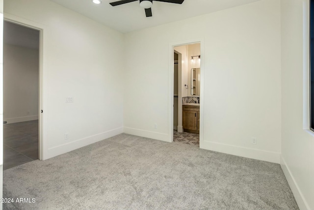 unfurnished bedroom with ceiling fan, light carpet, and ensuite bath