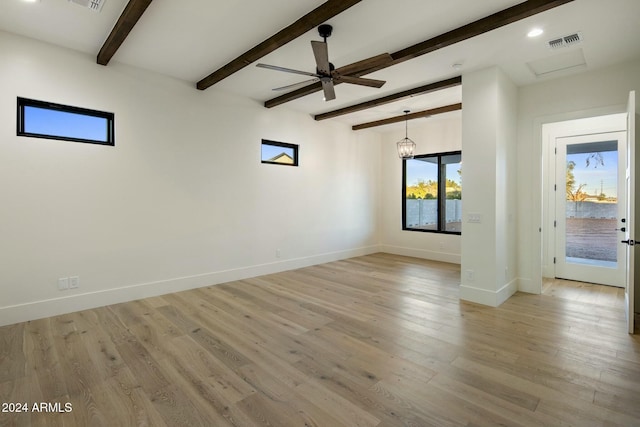 spare room with ceiling fan with notable chandelier, beam ceiling, and light hardwood / wood-style floors