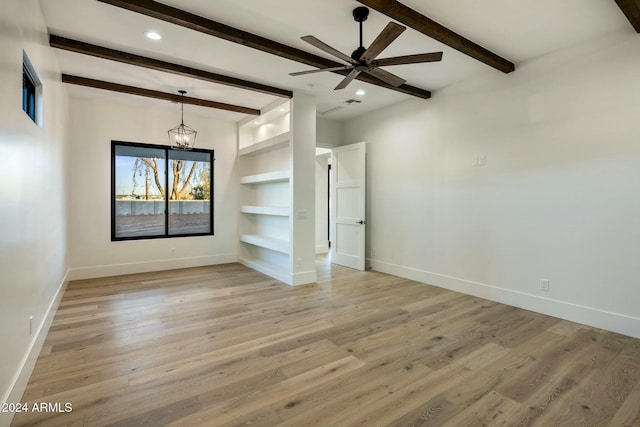 empty room featuring ceiling fan with notable chandelier, beam ceiling, built in shelves, and light hardwood / wood-style floors