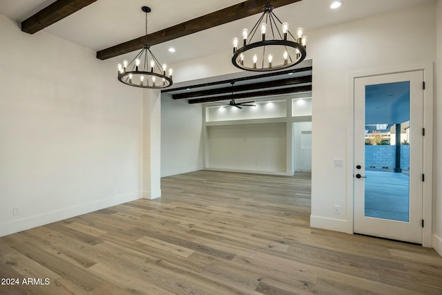 unfurnished dining area featuring beamed ceiling, ceiling fan with notable chandelier, and hardwood / wood-style flooring