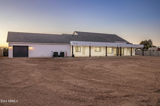 back house at dusk featuring a garage and cooling unit