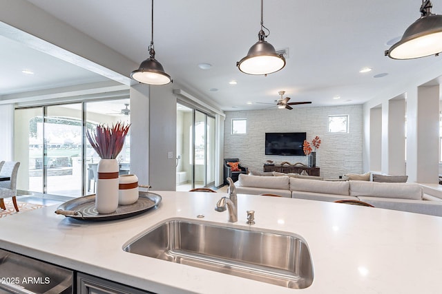 kitchen with ceiling fan, open floor plan, light countertops, hanging light fixtures, and a sink