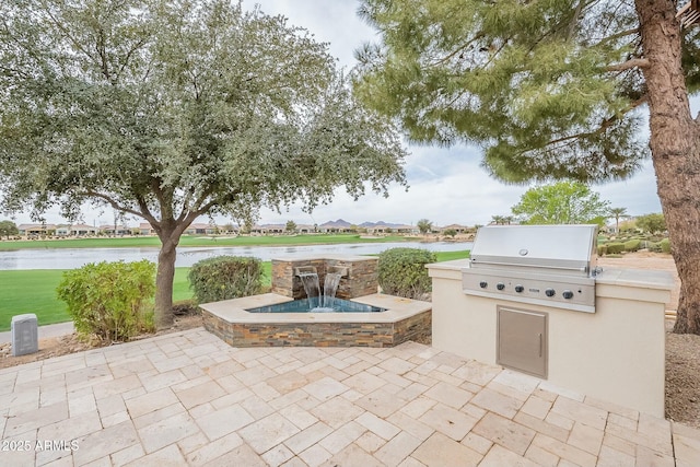 view of patio / terrace featuring a grill, exterior kitchen, and a water view