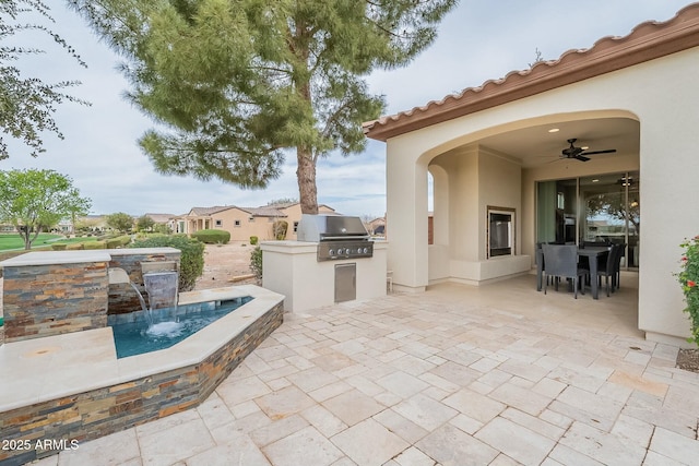 view of patio with an outdoor kitchen, outdoor dining space, ceiling fan, and grilling area