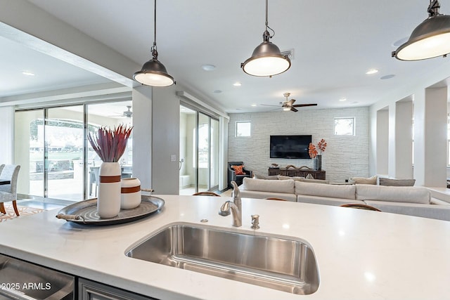 kitchen with open floor plan, pendant lighting, light countertops, and a sink