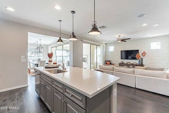 kitchen featuring gray cabinetry, dark wood finished floors, open floor plan, light countertops, and a sink