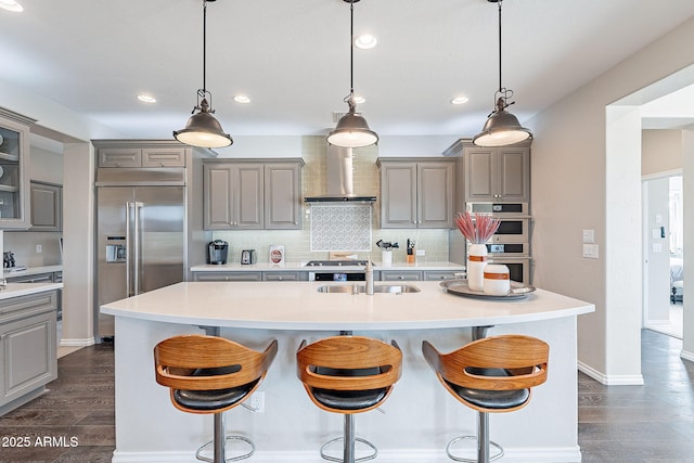 kitchen featuring a sink, a breakfast bar area, appliances with stainless steel finishes, and gray cabinetry