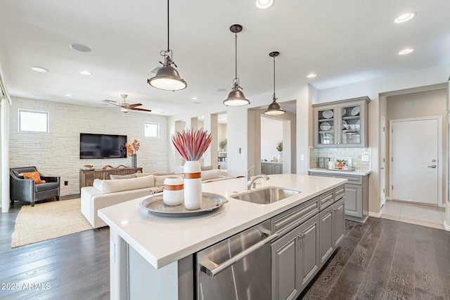 kitchen with gray cabinets, dark wood-style flooring, a sink, light countertops, and stainless steel dishwasher