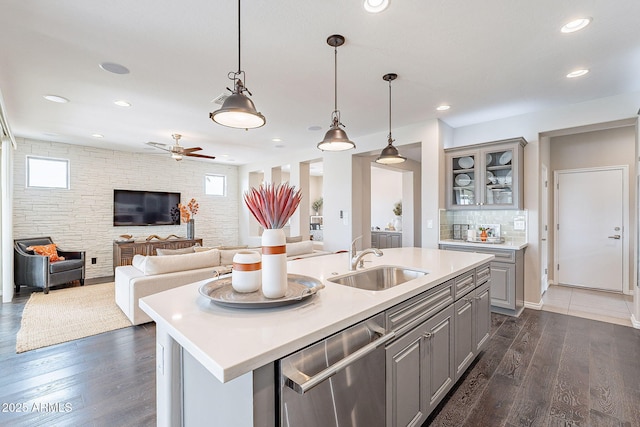 kitchen featuring open floor plan, dishwasher, light countertops, gray cabinets, and a sink