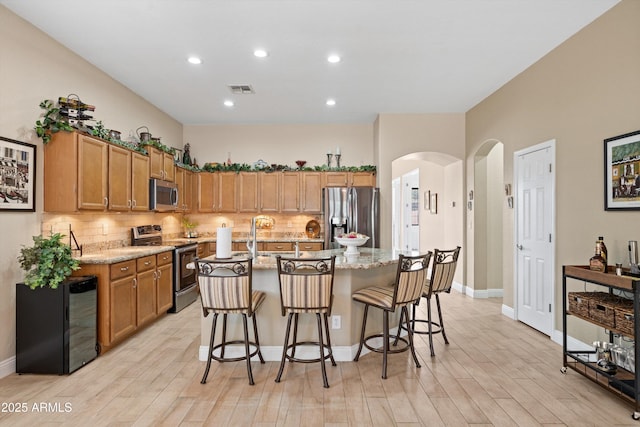 2221 W Calle De Las Estrella Way, Phoenix, AZ 85085 - kitchen with appliances with stainless steel finishes, arched walkways, light wood-style floors, backsplash, and recessed lighting