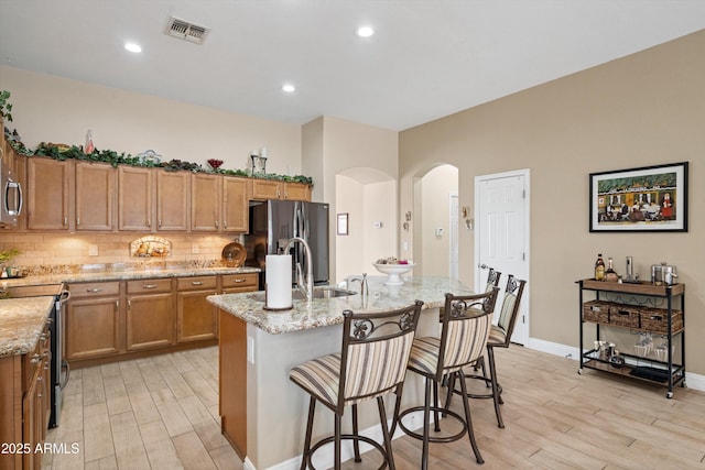 2221 W Calle De Las Estrella Way, Phoenix, AZ 85085 - kitchen with appliances with stainless steel finishes, light wood finished floors, arched walkways, light stone countertops, and recessed lighting