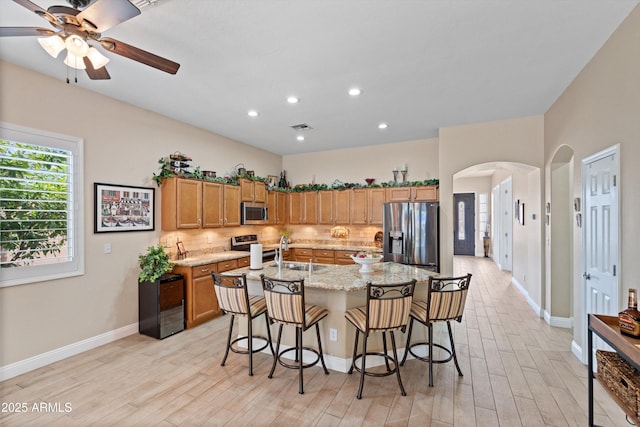 2221 W Calle De Las Estrella Way, Phoenix, AZ 85085 - kitchen featuring stainless steel appliances, arched walkways, backsplash, light wood-style flooring, and recessed lighting