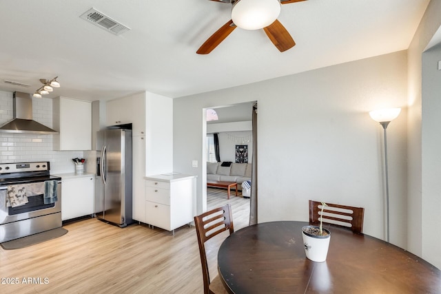 dining area featuring light wood-style floors, ceiling fan, and visible vents