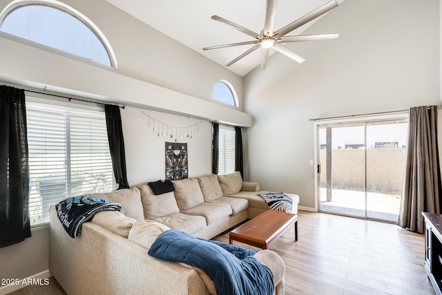 living area with baseboards, a ceiling fan, wood finished floors, and high vaulted ceiling