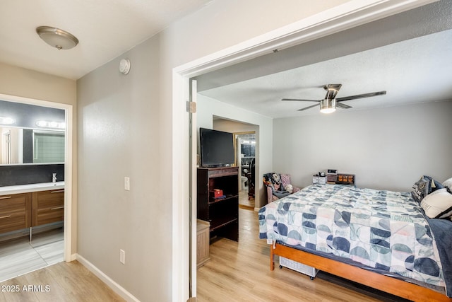 bedroom featuring baseboards, ensuite bathroom, and light wood-type flooring