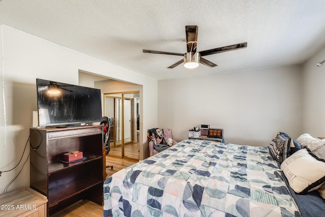 bedroom with a closet, ceiling fan, a textured ceiling, and light wood-type flooring