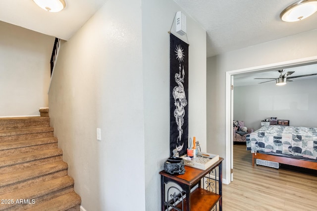 stairs featuring baseboards, ceiling fan, and wood finished floors
