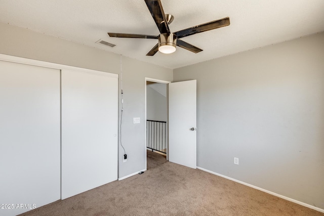 unfurnished bedroom with ceiling fan, carpet, a closet, and visible vents