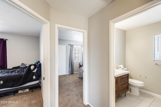 ensuite bathroom with vanity, baseboards, toilet, and connected bathroom