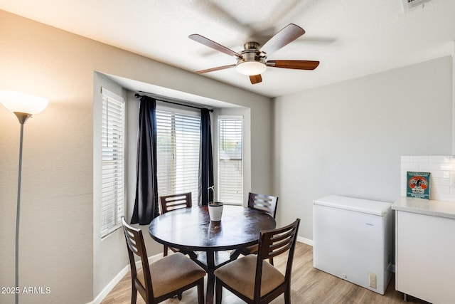 dining space featuring baseboards, ceiling fan, and light wood finished floors