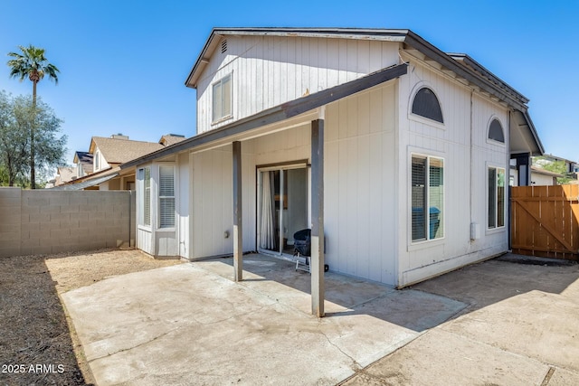 rear view of property with a gate, a patio area, and fence