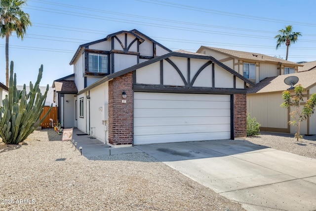 tudor home with an attached garage, fence, driveway, and brick siding