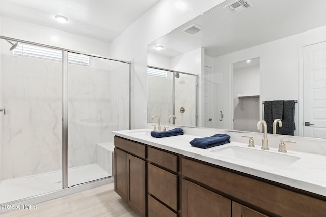 bathroom featuring a sink, visible vents, and a marble finish shower