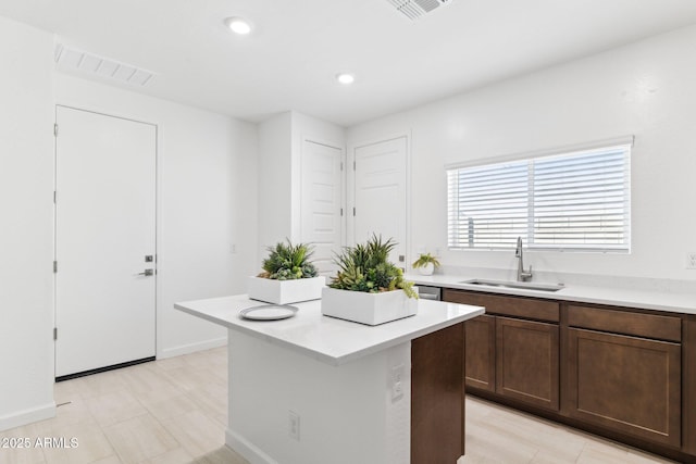 kitchen with light countertops, a center island, visible vents, and a sink