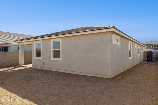 view of side of property featuring fence and stucco siding