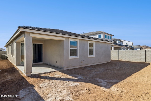 rear view of house featuring a patio area, central air condition unit, fence, and stucco siding