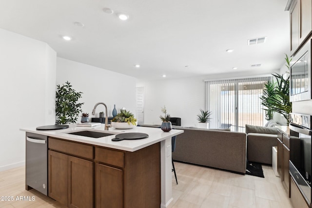 kitchen with visible vents, a sink, open floor plan, light countertops, and dishwasher