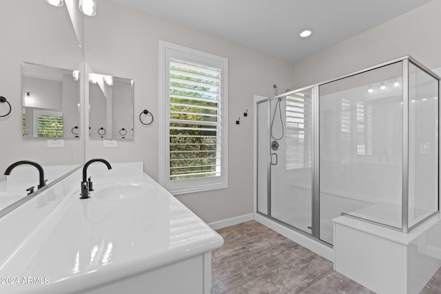 bathroom with hardwood / wood-style flooring, a shower with door, and vanity