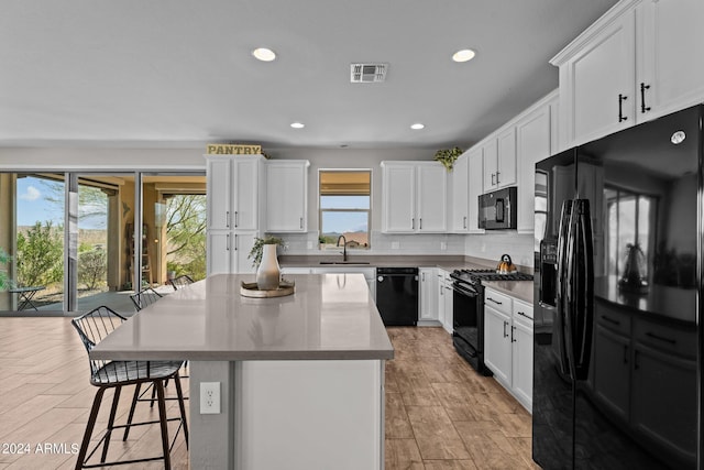 kitchen with a center island, white cabinetry, a healthy amount of sunlight, and black appliances