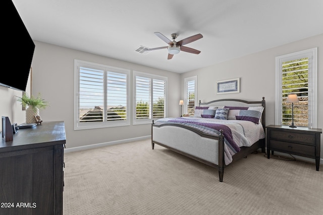 carpeted bedroom featuring multiple windows and ceiling fan