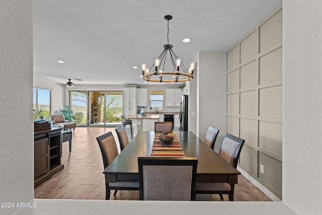 dining space with ceiling fan with notable chandelier, light hardwood / wood-style floors, and sink