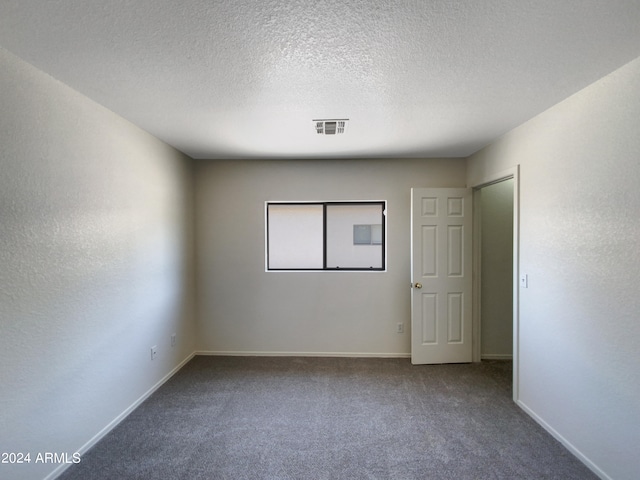 carpeted empty room featuring a textured ceiling