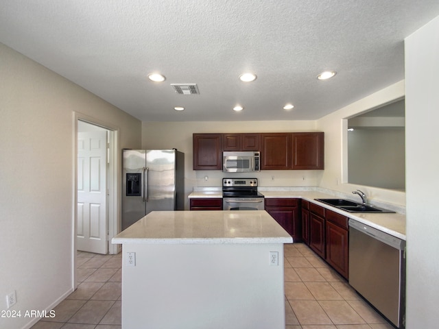 kitchen with a center island, sink, light tile floors, and appliances with stainless steel finishes