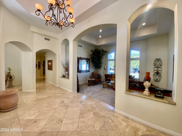 corridor featuring a raised ceiling and a chandelier